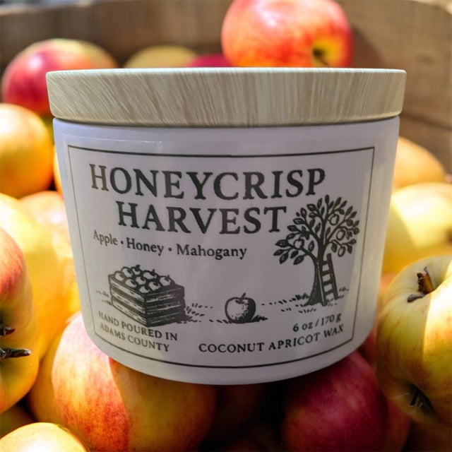 Honeycrisp Harvest candle with a wooden lid sitting on a pile of apples